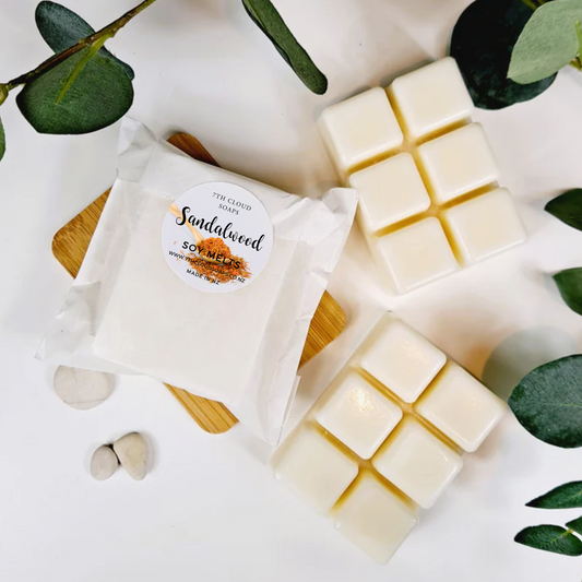 Sandalwood soy wax melts with packaging on a white surface with green leaves.