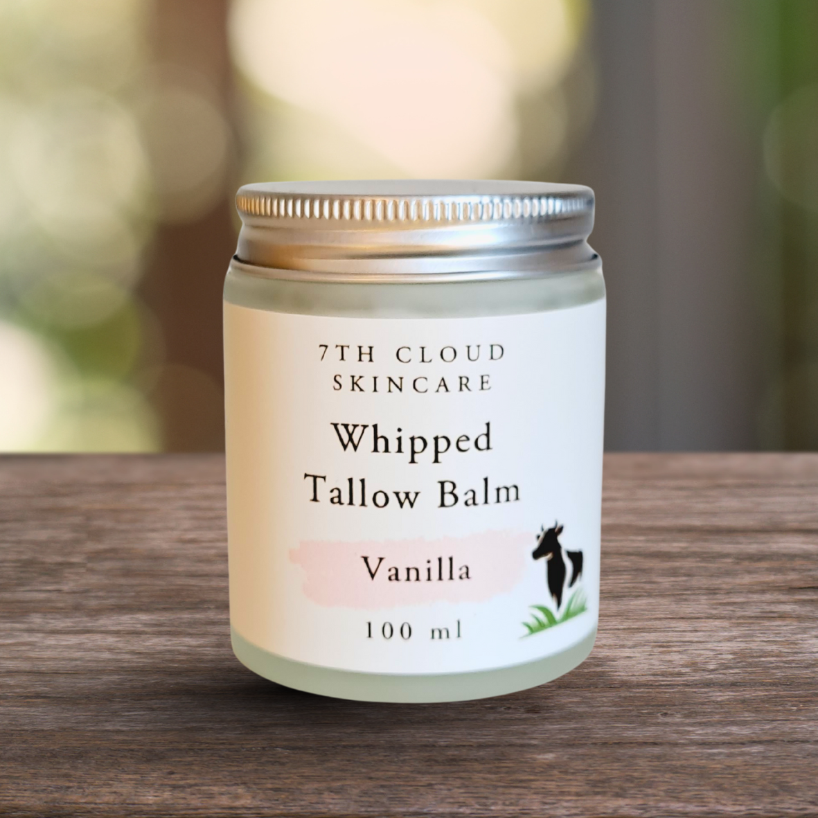 Jar of 7th Cloud Skincare Whipped Tallow Balm on a wooden surface with a blurred natural background