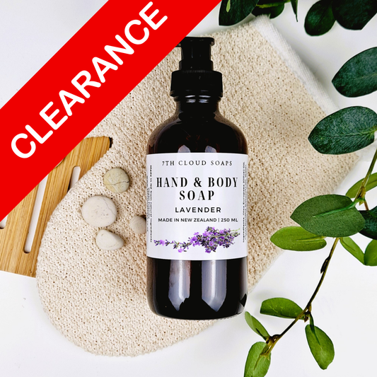 Hand and body soap bottle with lavender scent on a natural stone surface with green leaves.