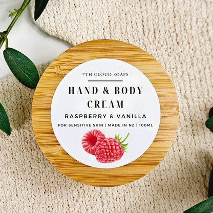 Hand and body cream container with raspberry and vanilla label on a textured surface.