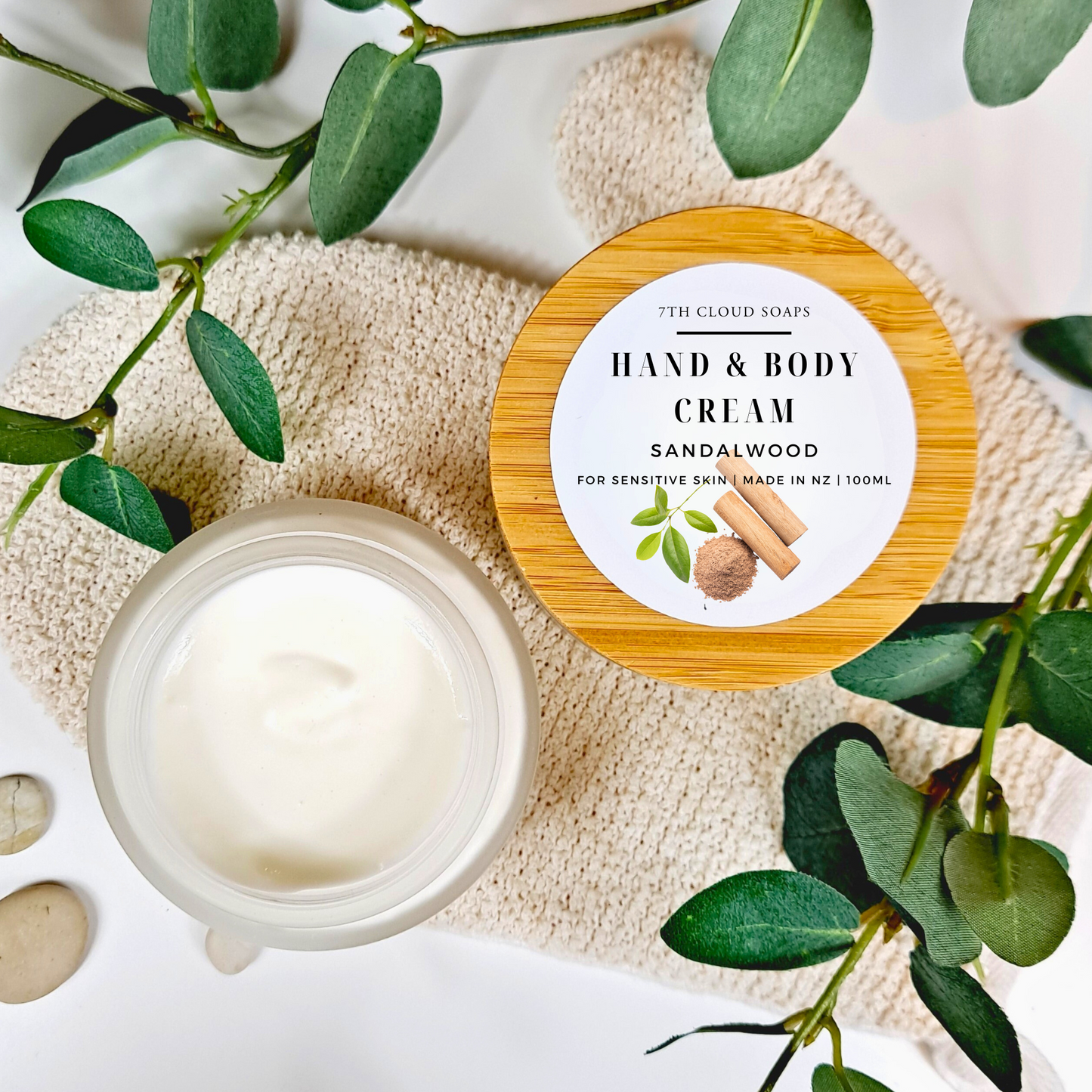 Hand and body cream with sandalwood scent on a natural background with green leaves.