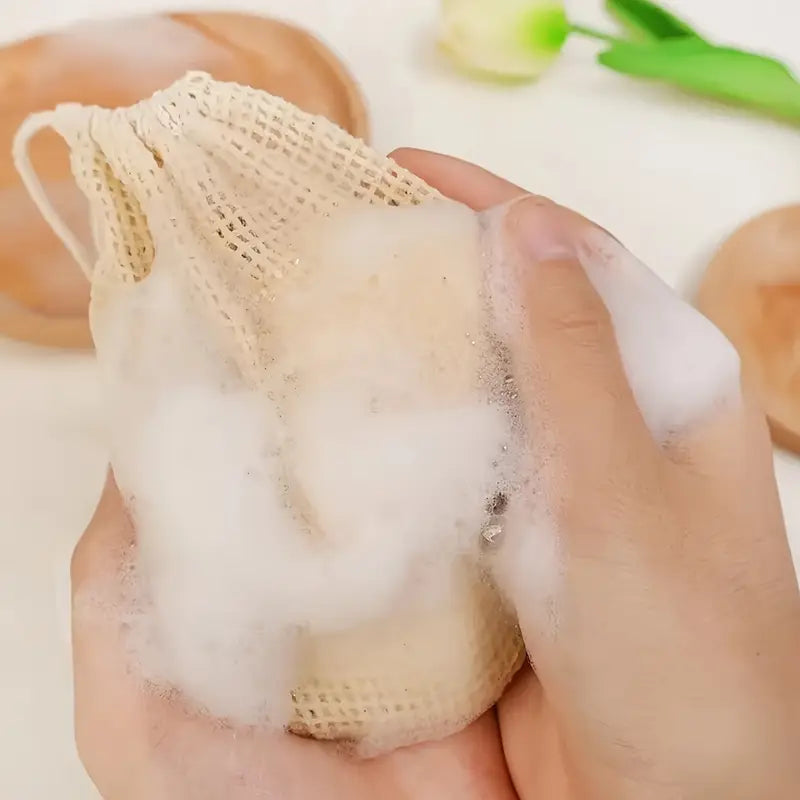 Hand holding a mesh bag with soap and foam, with a blurred background