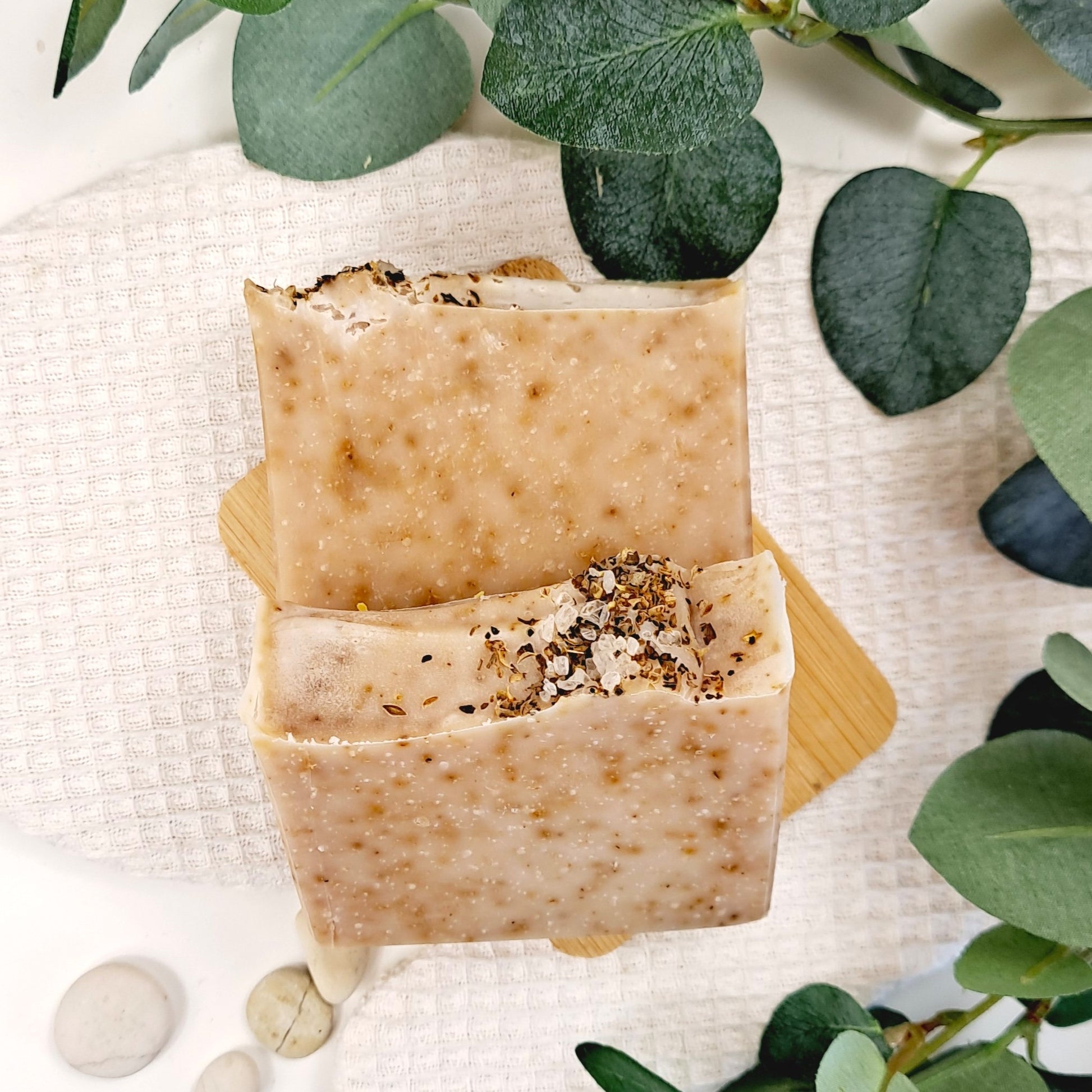 Two bars of natural soap with green leaves on a light background