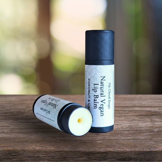 Two natural vegan lip balms on a wooden surface with a blurred green background