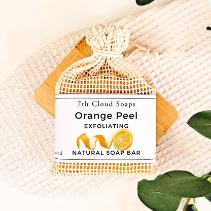 Orange Peel Exfoliating Natural Soap Bar from 7th Cloud Soaps on a textured surface with leaves.