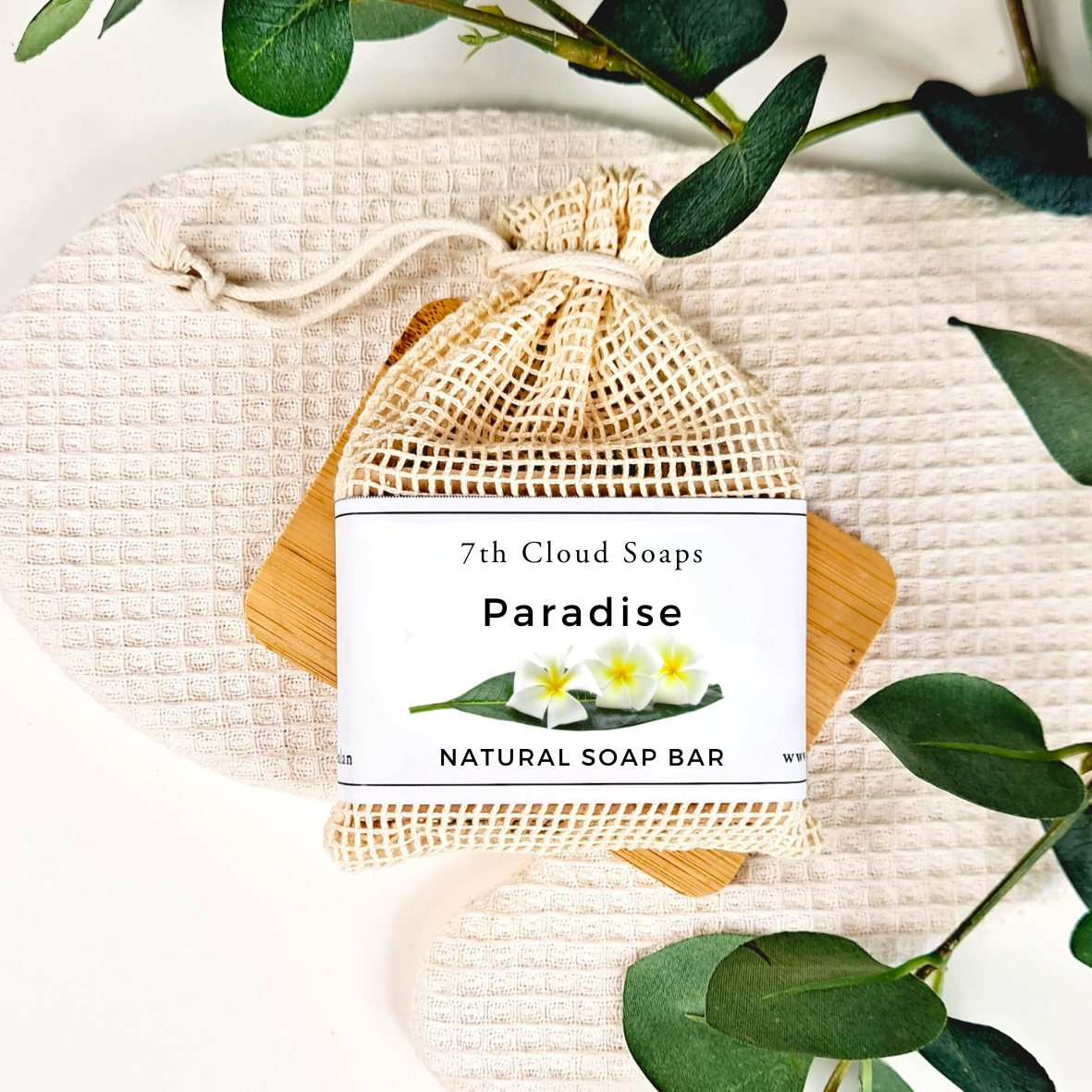 7th Cloud Soaps Paradise natural soap bar in a mesh bag with green leaves on a light background