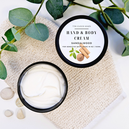 Hand and body cream in a jar with a label on a textured surface with green leaves.