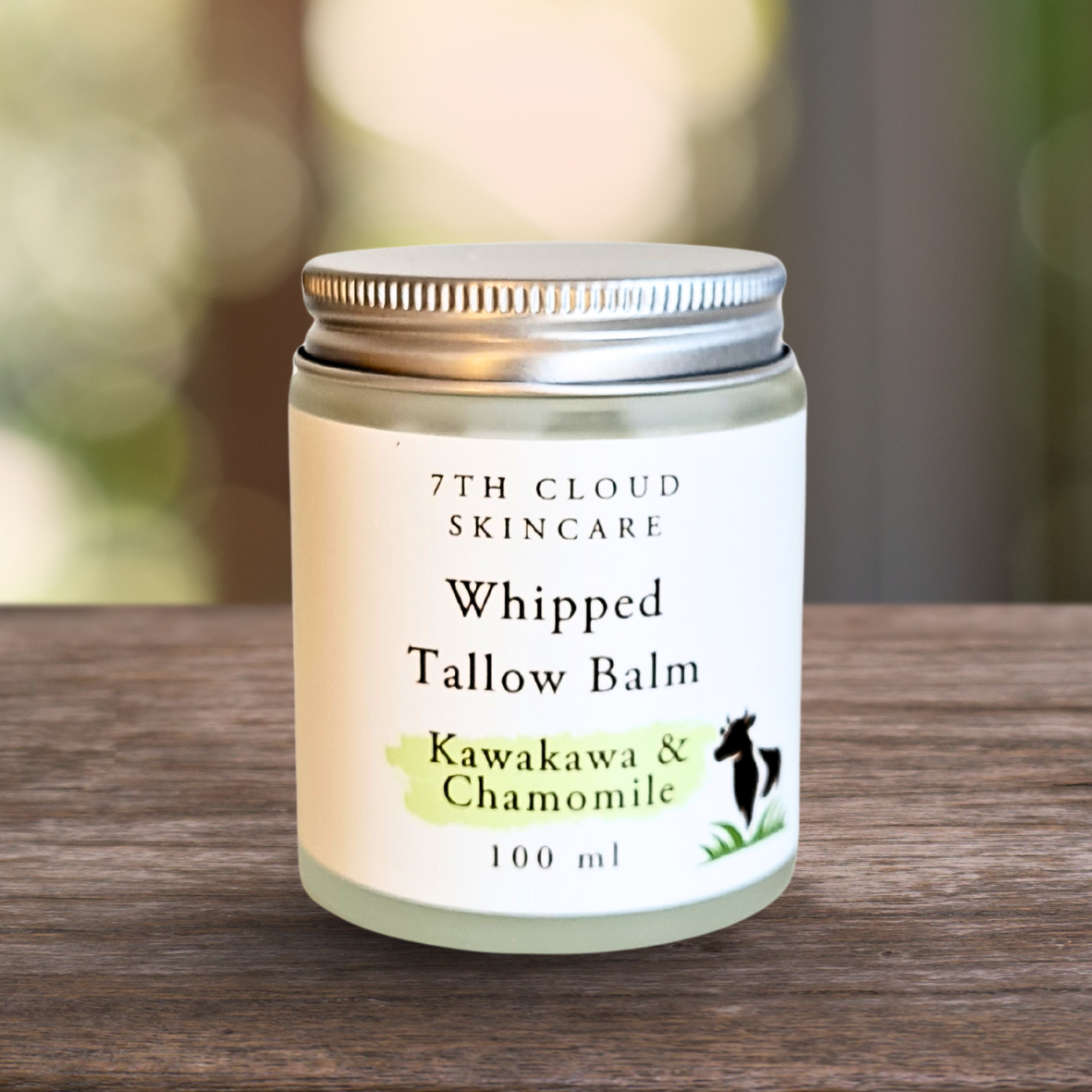Jar of 7th Cloud Skincare Whipped Tallow Balm on a wooden surface with a blurred natural background