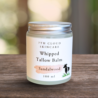 Jar of 7th Cloud Skincare Whipped Tallow Balm Sandalwood on a wooden surface with a blurred natural background