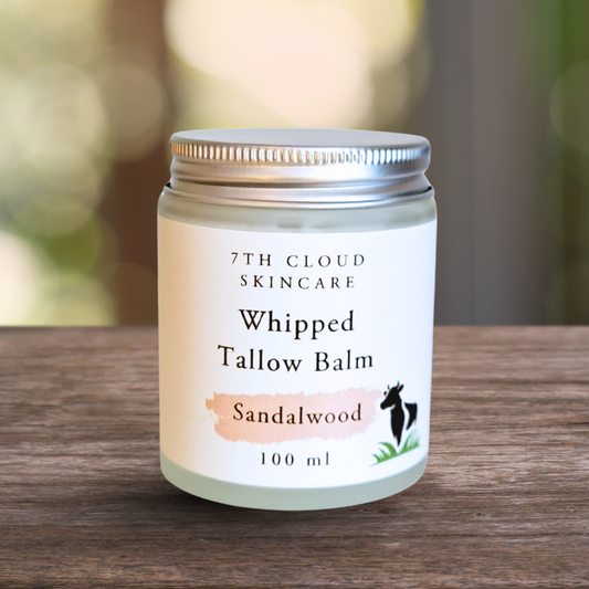 Jar of 7th Cloud Skincare Whipped Tallow Balm Sandalwood on a wooden surface with a blurred natural background