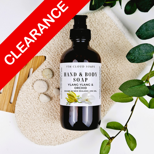 Bottle of hand and body soap with a label on a textured surface with green leaves.